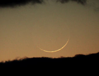 雲間にやっと見つけた今日の月、「二日月」。沈んだ太陽にとても近いので、月の背景はまだ明るく、肉眼では分からないほどです。月齢わずか1.1。